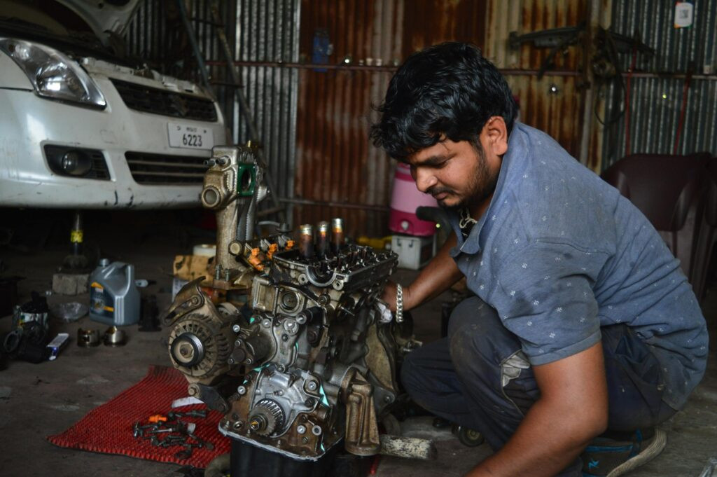 How to Reduce Repair Delays with Small Engine Shop Software 23 A mechanic works on an engine in a garage in India, showcasing auto repair skills.